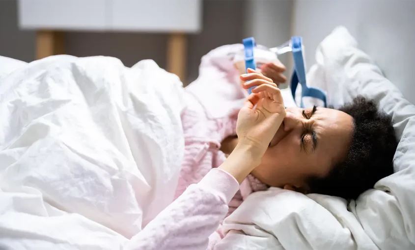 A woman lying in bed without sleep due to sleep apnea device