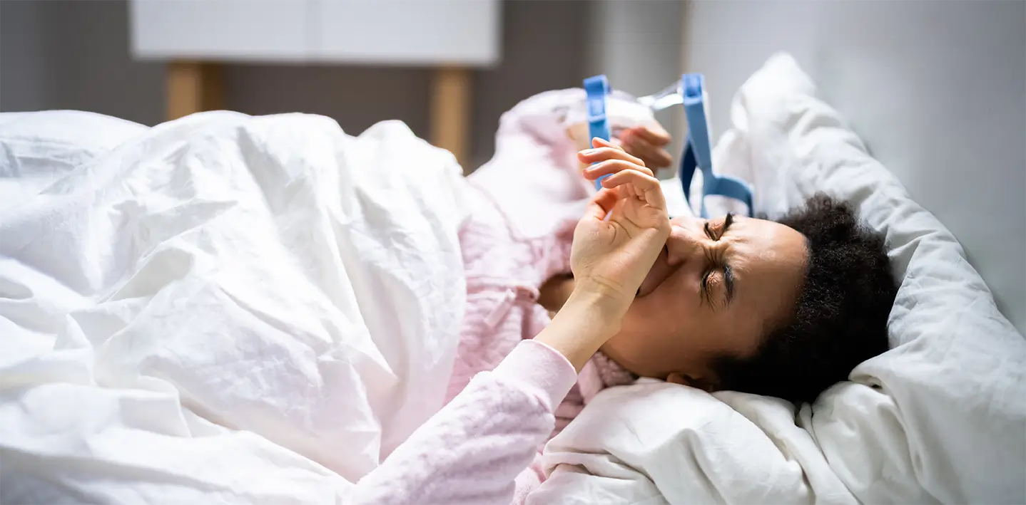 A woman lying in bed without sleep due to sleep apnea device